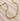 Gold necklace on a textured beige surface