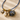 Necklace with shell and pearl charms on a sandy background