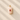 Pink stone pendant with a red gemstone on a textured beige surface