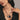 Woman wearing a necklace with blue cord and decorative elements against a neutral background