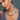 Woman wearing a turquoise beaded necklace with a cross pendant against a gray background