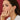 Woman wearing gold jewelry against a red background