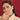 Woman wearing gold jewelry against a red background