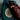 A hand wearing a dark burgundy leather glove and gold rings holds a vintage teal rotary telephone against a muted blue-gray background.